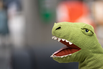 A dinosaur (T-rex) pillow doll in action of biting. Close-up and selective focus at the head.