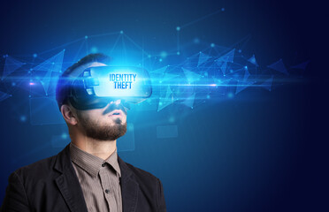 Businessman looking through Virtual Reality glasses with IDENTITY THEFT inscription, cyber security concept