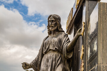 Escultura simbolizando Jesus Cristo em topo de mausoléu dentro de um cemitério.