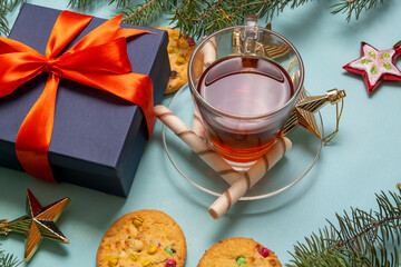 a Cup of warm tea is surrounded by Christmas cookies, Christmas toys and fir branches