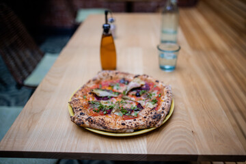 Vegan pizza on a table alongside a bottle of dressing and a glass of water