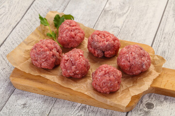 Raw meatball over wooden background