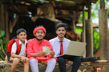 Young indian farmer showing money with agronomist or banker at home