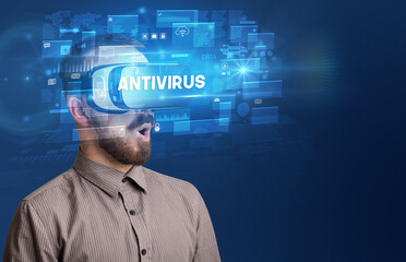 Businessman looking through Virtual Reality glasses with ANTIVIRUS inscription, innovative security concept