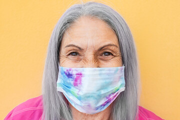 Happy senior woman wearing face mask during coronavirus outbreak - Covid-19 old people lifestyle...