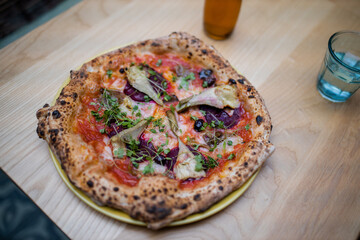 Vegan pizza on a table alongside a bottle of dressing and a glass of water