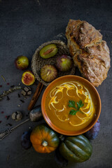 Pumpkin soup with fresh baked bread and silver spoon on gray table. Top view photo of vegan meal. Healthy eating concept. 
