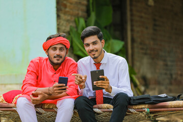 Obraz premium Young indian agronomist or banker showing some information to farmer in smartphone