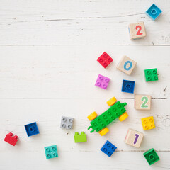 Developing multi-colored cubes on a white wooden table. Wooden cubes with numbers 2021 and others. Top view of the numbers of the year and other educational toys.