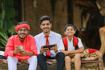 indian farmer and agronomist or banker showing smartphone and money at home