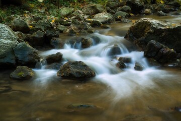 The stream of water in the river flowing between the rocks , long exposure photo