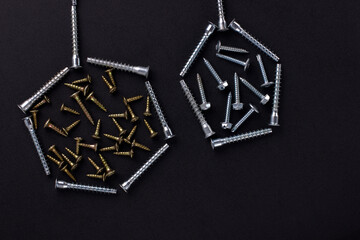 Abstract shapes and background for text made of self-tapping screws and furniture screws on a black background (top view).