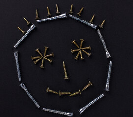 The outline of a smile is made of self-tapping screws on a black background (top view).