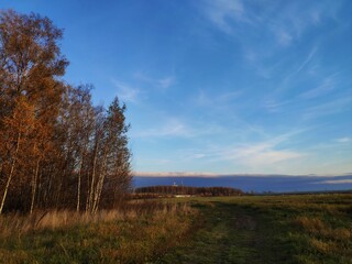 Obraz premium dramatic sky with clouds on the sunset, clouds like a wave with white foam, a wide field and autumn forest