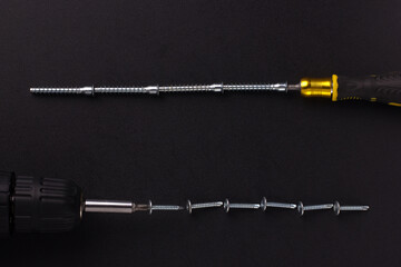 the background for the text is made of screws, furniture screws, a screwdriver, a screwdriver on a black background (top view).