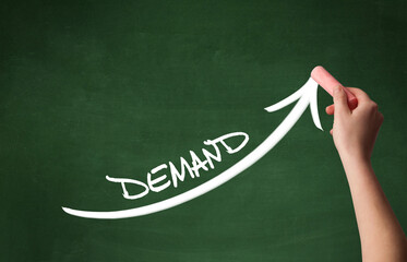 Hand drawing DEMAND inscription with white chalk on blackboard, business concept