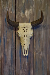 Decorative bull skull hangs on an antique wooden background for interiors. Designer bone element in living room. Concept of hunting, production, interior design. Copy space