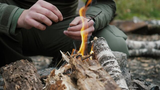 The fire flares up. A man makes a fire in the forest during the day. Close-up. Slow motion 180 frames per second.