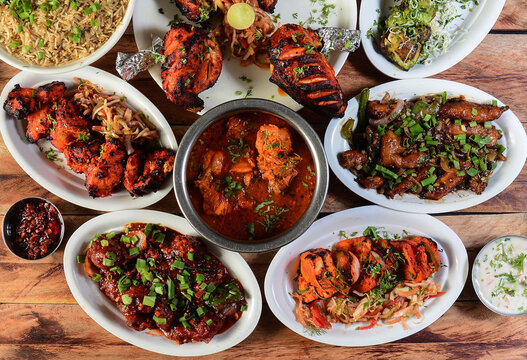 Assorted indian foods chicken pahadi kebab,chicken angara kebab,tandoori chicken,pepper chicken, paneer tikka and chicken masala on wooden background. Dishes and appetizers of indian cuisine