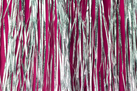 Shiny Holographic Tinsel On Dark Pink Background. Festive Or Party Backdrop.