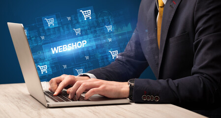 Businessman working on laptop with WEBSHOP inscription, online shopping concept