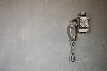 Fototapeta na wymiar Old vintage wired telephone for communication hangs on textured gray wall. Antique phone from past for background. History of telephone in world. Concept of communications and telegraph. Copy space