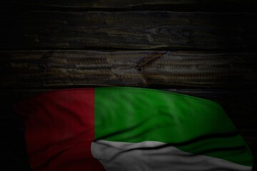 nice dark image of United Arab Emirates flag with large folds on old wood with empty space for text - any occasion flag 3d illustration..