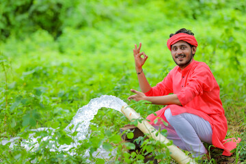 indian farmer with water flow from pipe at field