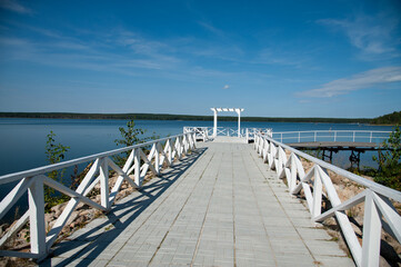Empty pier on the background of a beautiful lake on a bright sunny day