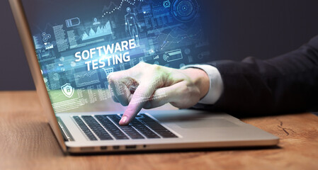 Businessman working on laptop with SOFTWARE TESTING inscription, cyber technology concept