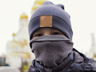 A portrait unrecognizable kid with homemade COVID19 protection stopped in front of an Orthodox church.