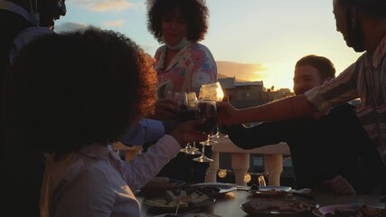 Young multiracial friends toasting with red wine glasses during appetizer sunset time while wearing face protective mask