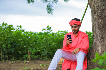 Young indian farmer using smartphone at home