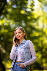 Portrait of a smiling beautiful woman talking on the phone in the park