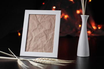 Vertical white picture frame on dark table with bokeh background
