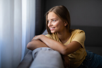 Beauty woman with white perfect smile looking at camera relaxing at couch at home