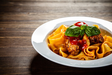Pasta with meatballs in tomato sauce on wooden table
