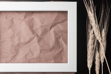 Horizontal white picture frame on dark table with wheat