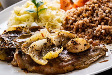 Roasted meat, buckwheat and sauerkraut on wooden table