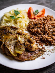 Roasted meat, buckwheat and sauerkraut on wooden table