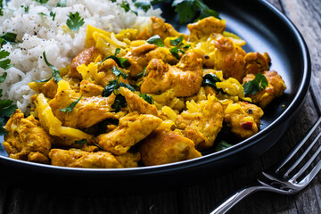 Chicken meat with rice and vegetables on wooden table
