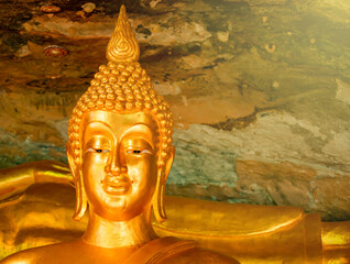 Golden yellow buddha statue Was built in a cave in the temple area