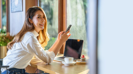 Portrait Young Asian woman holding and drinking a cup of coffee and working with technology laptop at a coffee shop. freelancer and entrepreneur working by connecting to internet via computer