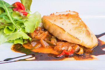 Delicious healthy grilled fish fillet served on a platter with a colorful fresh salad for a tasty seafood. Grilled Snow fish