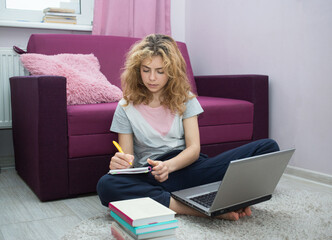 nice girl - teenager of 17 years old, preparing for exams at home, sitting on floor in front of...