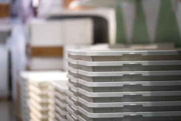 Stack of white clothing basket which is sale on the product shelf in the department store. Close-up and selective focus at the basket's handle part.