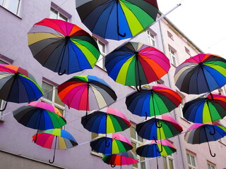 Kolorowe parasolki zawieszone między blokami wysoko nad ulicą