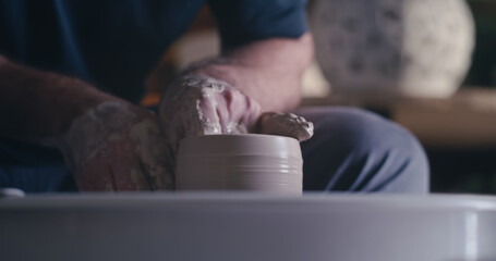 Crop ceramist shaping pot with wet hands