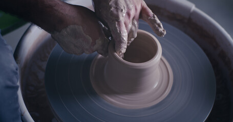 Crop ceramist creating pot on spinning wheel