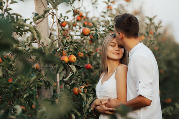 Guy in white shirt kissing tender his girlfriend's forehead. The girl in white dress smiles with...